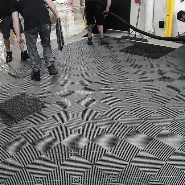 Workers installing gray vented interlocking floor tiles