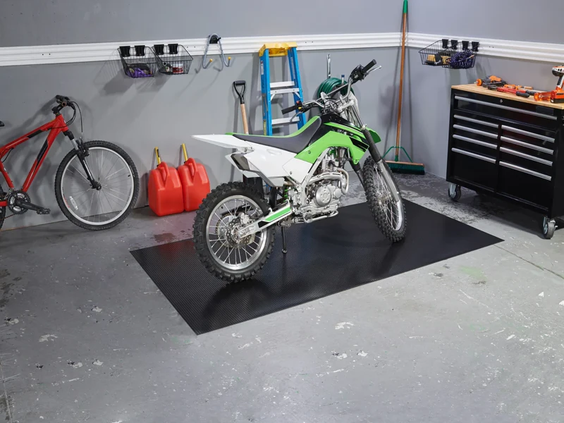 bike parked on a black ribbed motorcycle mat in a organized garage