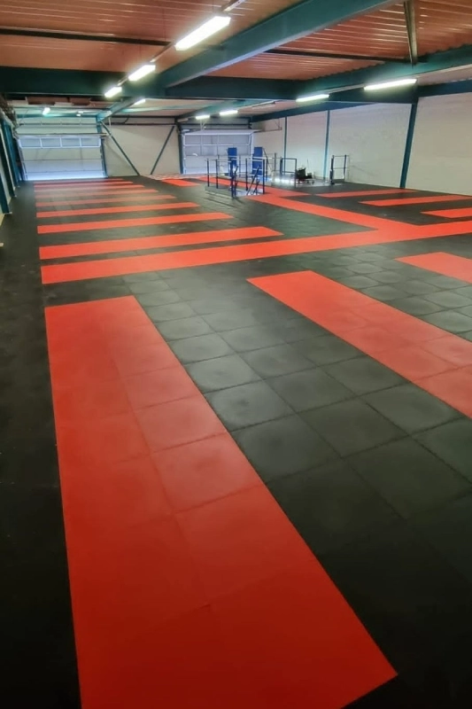 _ Heavy-duty interlocking PVC garage flooring with a custom red and black pattern in a commercial garage.