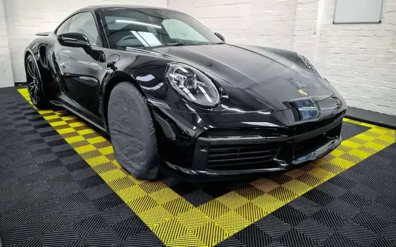Vented rubber garage flooring tiles featuring a custom yellow border and black diamond-grid texture